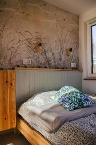 a bed in a bedroom with a wall at Bujanie w sitowiu in Wyszowate