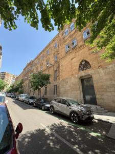 una fila de autos estacionados frente a un edificio de ladrillo en Apartamento Céntrico , Cómodo, Tranquilo y con WiFi, en Salamanca