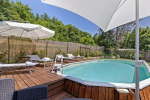 a swimming pool with an umbrella and chairs and a table at Casa Serena, Radda In Chianti in Radda in Chianti