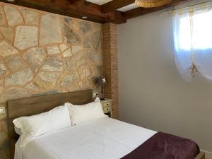 a bedroom with a bed and a stone wall at Alojamiento Cerro Socorro in Cuenca +76 photos