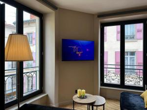 a living room with windows and a couch and a table at Cocon en centre ville in Le Puy en Velay +2 photos