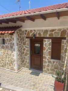 a house with a wooden door and a stone wall at APARMENTS Elina in Potamiá