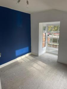 une pièce vide avec un mur bleu et une fenêtre dans l'établissement Grimsby Central Luxury 2 Bedrooms, Pelham 1, à Great Coates