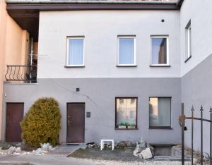 a white house with brown doors and a fence at Apartamenty Głowackiego in Sosnowiec