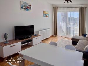 a living room with a flat screen tv and a table at Baltic Zen II - Apartament in Hel