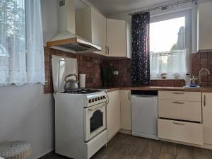 a kitchen with a white stove top oven next to a window at Chata nad Rzeką in Lipusz