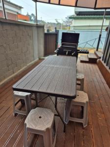 Una mesa de picnic y taburetes en una terraza con parrilla. en Laon Haje, Joyful Tomorrow, en Buyeo