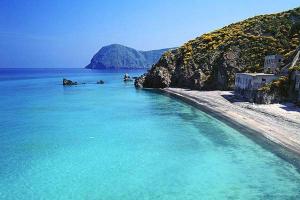 a beach with blue water next to a mountain at CasaEolia Blues in Canneto +22 photos