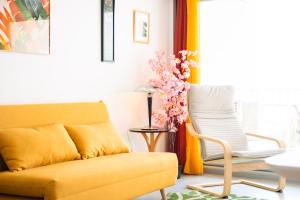 ein Wohnzimmer mit einem gelben Sofa und einer Vase aus Blumen in der Unterkunft Nouveau T2 Horizon Vue Mer Palavas in Palavas-les-Flots