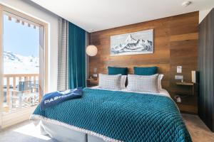 a bedroom with a bed with a blue comforter at Hotel Pashmina Le Refuge in Val Thorens