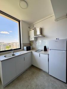 a kitchen with white cabinets and a large window at Studio 616 SunnyVibes in Mamaia Nord