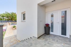 a white house with a door and a courtyard at Apartmani Summer in Kolan