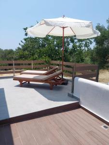 a patio with an umbrella and two lounge chairs at Summer Project Theros in Nea Kalikratia