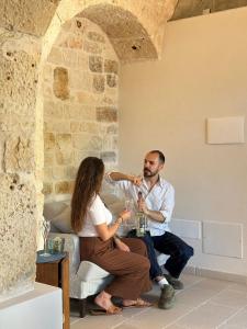 a man and a woman sitting on a chair drinking wine at Masseria Mazzalorsa in Alberobello