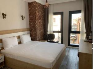 a bedroom with a white bed and a brick wall at Ayvalik Cihan Otel in Ayvalık +5 photos