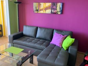 ein Wohnzimmer mit einem Sofa und einer lila Wand in der Unterkunft Großzügige Ferienwohnung mit Atlantikblick in zentraler Lage Monte Rojo San Agustín in San Bartolomé de Tirajana