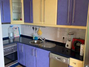 eine Küche mit lila Schränken und einem Waschbecken in der Unterkunft Großzügige Ferienwohnung mit Atlantikblick in zentraler Lage Monte Rojo San Agustín in San Bartolomé de Tirajana