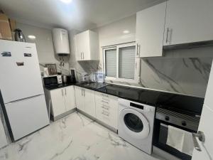 a kitchen with white cabinets and a washer at Luxury flat Mar de Cristal in Mar de Cristal