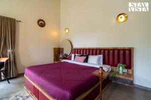 a bedroom with a bed with a purple blanket at StayVista at Bayleaf Villa with Pool, Lawn, Wi-Fi in Nashik +24 photos