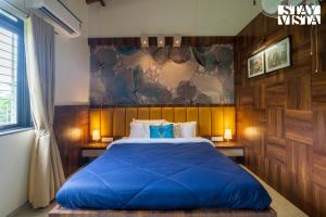 a bedroom with a large bed with blue sheets at StayVista at Bayleaf Villa with Pool, Lawn, Wi-Fi in Nashik