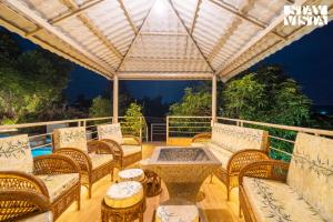 a patio with wicker chairs and a table and a pergola at StayVista at Bayleaf Villa with Pool, Lawn, Wi-Fi in Nashik