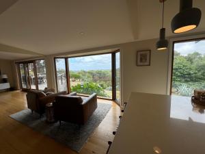 a living room with couches and a table and windows at Ocean View Farm in Red Hill South