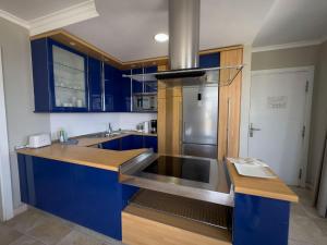eine Küche mit blauen Schränken und einem Kühlschrank aus Edelstahl in der Unterkunft Holiday Club Vista Amadores in Amadores