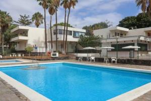 a swimming pool in front of a house at Estudio con Encanto, Piscina, BBQ y Terraza para una Estancia Ideal in Costa Del Silencio