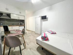 a white kitchen with a table and a counter top at Estudio con Encanto, Piscina, BBQ y Terraza para una Estancia Ideal in Costa Del Silencio
