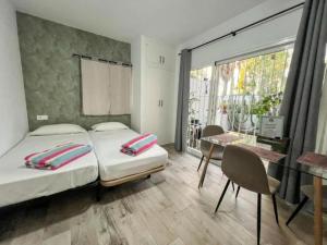 a bedroom with two beds and a table and a window at Estudio con Encanto, Piscina, BBQ y Terraza para una Estancia Ideal in Costa Del Silencio +21 photos