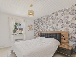 - une chambre avec un lit et un mur recouvert de papier peint dans l'établissement Maison moderne et piscine commune, à Les Sables-dʼOlonne