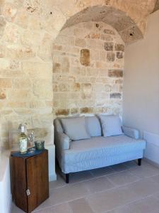 a couch sitting in a room with a stone wall at Masseria Mazzalorsa in Alberobello +79 photos
