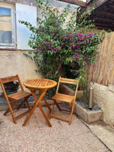 two chairs and a wooden table and chairs next to a plant at Studio Bougainvillier in La Seyne-sur-Mer
