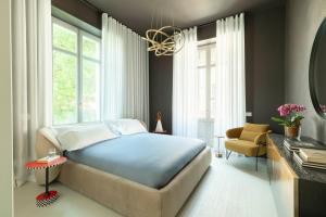 a bedroom with a bed and a chair and a mirror at 10 Manzoni Aparthotel in Cremona +117 photos