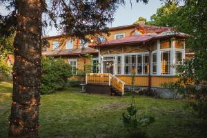 a large yellow house with a tree in the yard at Villa14 - Noisy Party Hostel in Pärnu