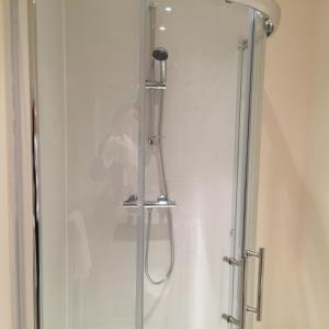 a shower with a glass door in a bathroom at Bruce's Cottage in Stirling