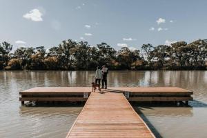 two people and a dog on a dock in a lake at Long Island Retreat - Pelican in Murray Bridge