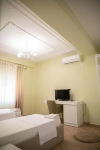 a room with two beds and a desk with a computer at Hotel Merkaj in Berat