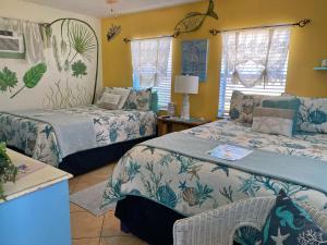two beds in a room with yellow walls at SI COMO NO INN in Flagler Beach