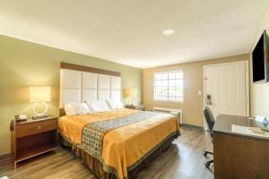 a hotel room with a bed and a desk at Deluxe Inn & Suites By OYO Miami OK in Miami