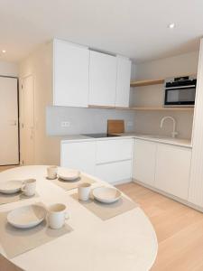 Una cocina blanca con una mesa con cuencos y tazas encima. en Studio Nacre Knokke, en Knokke-Heist