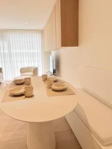 a white table in a room with cups and plates on it at Studio Nacre Knokke in Knokke-Heist