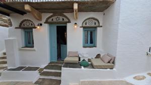 a porch of a house with two chairs and a table at Meli House Cycladic traditional stone house-1895 in Platiá