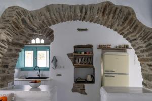 a kitchen with a stone archway and a refrigerator at Melina house Platia Tinos in Platiá