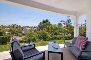 a porch with a couch and chairs and a table at Villa Rose in Albufeira