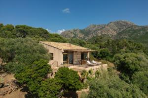 a house on a hill with mountains in the background at Signura, maison entre mer et maquis in Piana