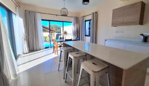 a kitchen with a large white counter and stools at Villa Ledgewood - Pereybere - Moderne, Calme & Piscine privée in Grand Baie