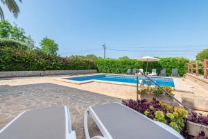 a swimming pool with two chairs and an umbrella at Apartment Soleado by Mallorca House Rent in Portocolom
