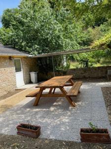 un tavolo da picnic in legno in un cortile con piante in vaso di maison en bord de Sarthe a Juigné-sur-Sarthe