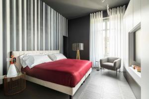 a bedroom with a large bed and a chair at 10 Manzoni Aparthotel in Cremona